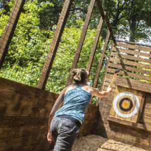 woman throws axe at outdoor target