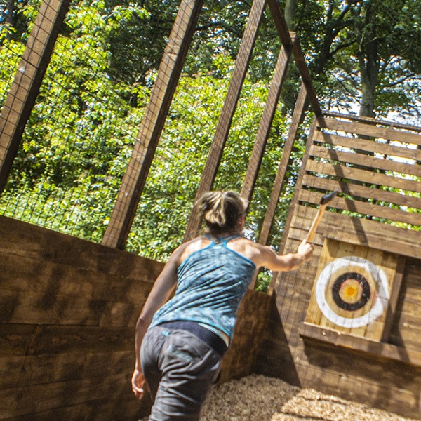 Woman throws an axe at an axe throwing target at an outdoor range