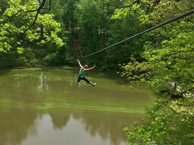 Woman ziplines over a pond