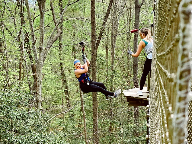 Woman ziplines to join her friend on a treetop platform