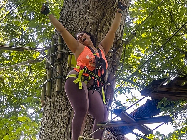 Woman celebrates tackling a treetop obstacle