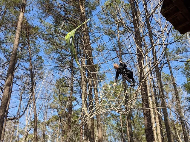 A young woman swings into a net at Go Ape zipline williamsburg