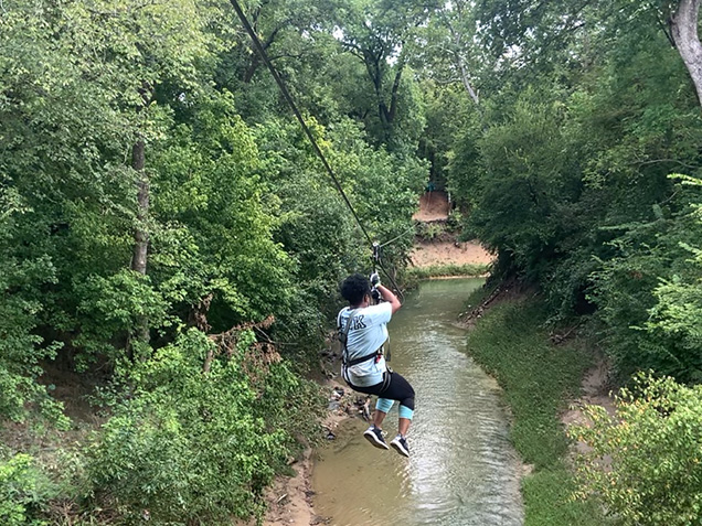 Woman ziplines over river