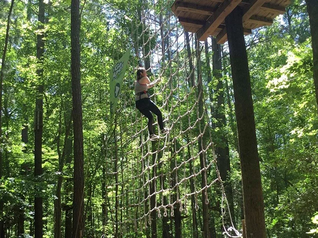 Woman climbs net after Tarzan swing