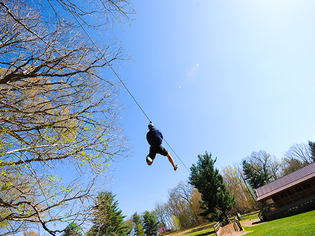 Climber ziplines across a field
