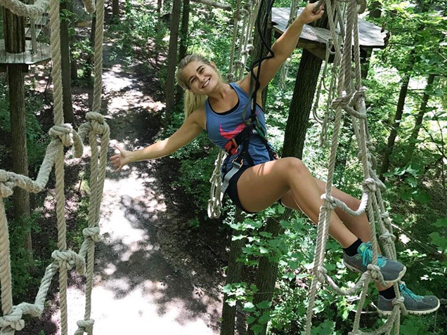 Young woman smiles as she climbs across nets
