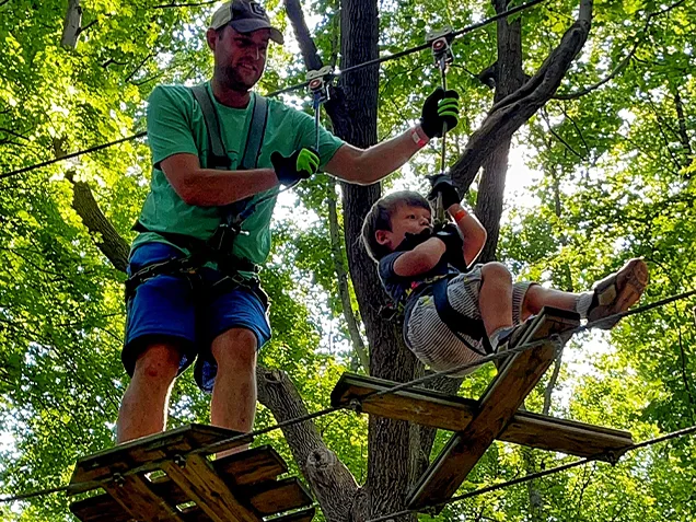 Family having fun on Go Ape outdoor adventure ropes course Bear. Delaware