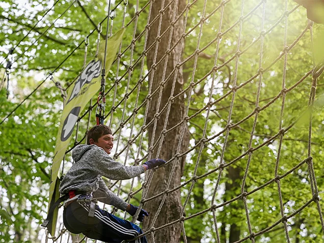 A young man having fun on Tarzan Swing at Go Ape outdoor adventure ropes course Indianapolis