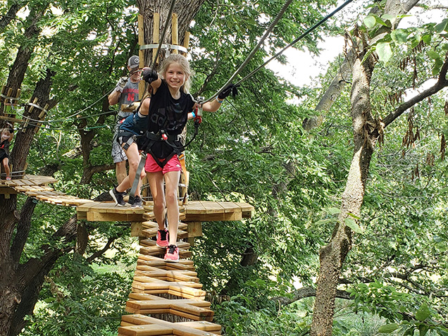 Smiling girl climbs across obstacle