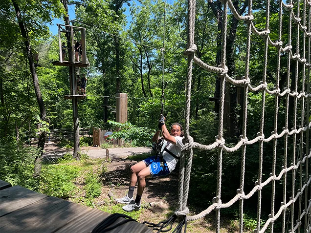 Man swings into the Tarzan swing at Go Ape outdoor adventure ropes course Kansas City