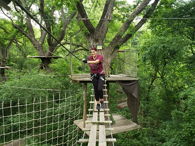 Woman climbs through the forest canopy