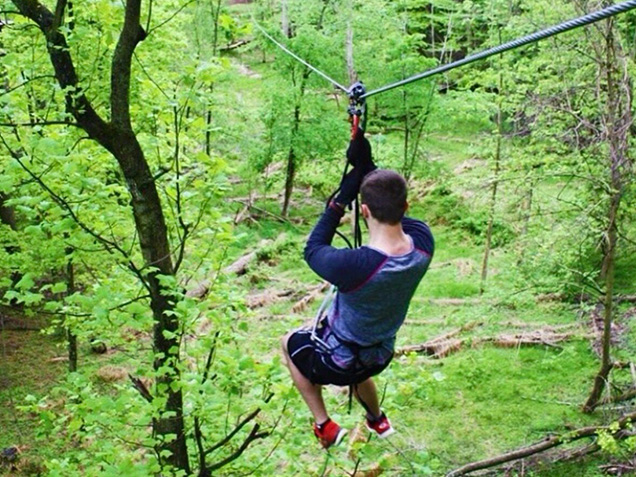Young man ziplines through the trees