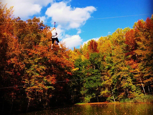 zipliner zipping across lake with autumn leaves