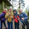 Young children smile and show off their harnesses