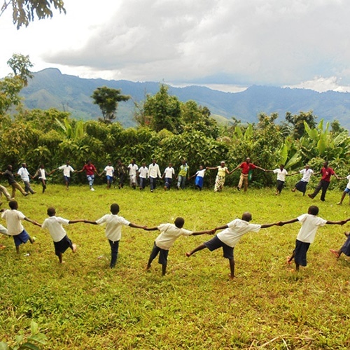 African villagers stand in a circle and hold hands