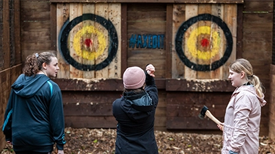 Teenage girls throw axes at axe throwing targets