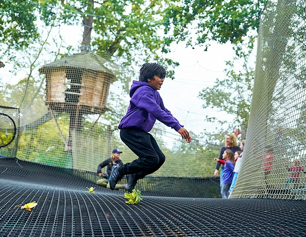 young boy jumping on sky high playground