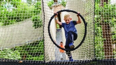 Young boy climbing treetop nets