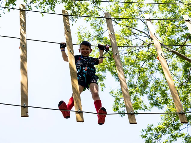 Boy climbs through Treetop Journey at Go Ape Zipline & Adventure Park Arlington