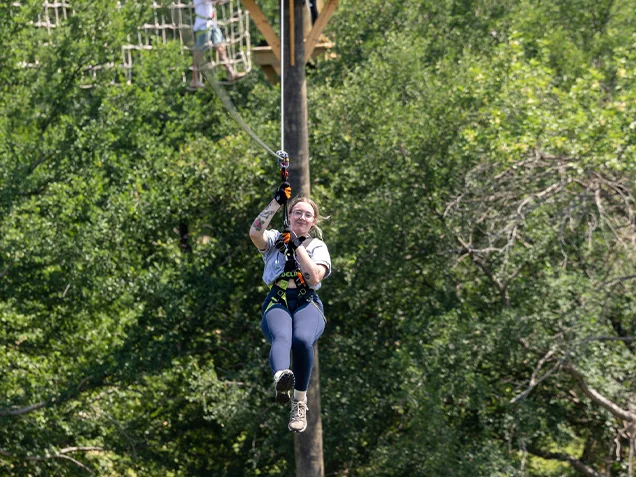 Young woman flies through the trees at Go Ape Zipline Arlington