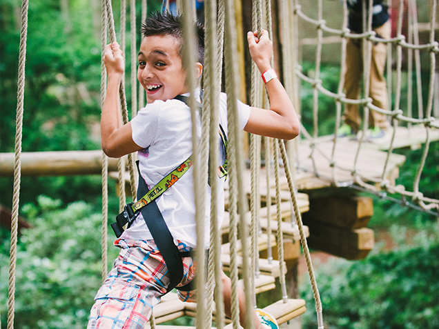 Young boy smiles while climbing obstacle