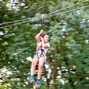 Young girl ziplining through the forest at Go Ape Zipline Arlington