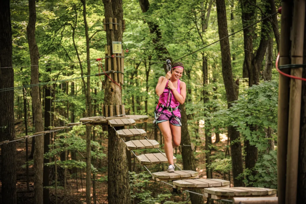 A young woman crosses a treetop bridge in the forest