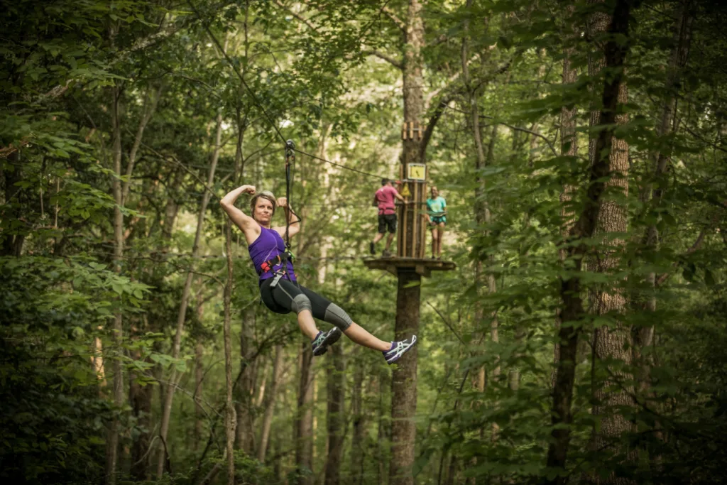 Train To Climb: Your Complete Go Ape Workout - A zipliner flexing her muscles